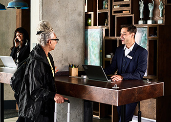 Man helping woman at reception desk